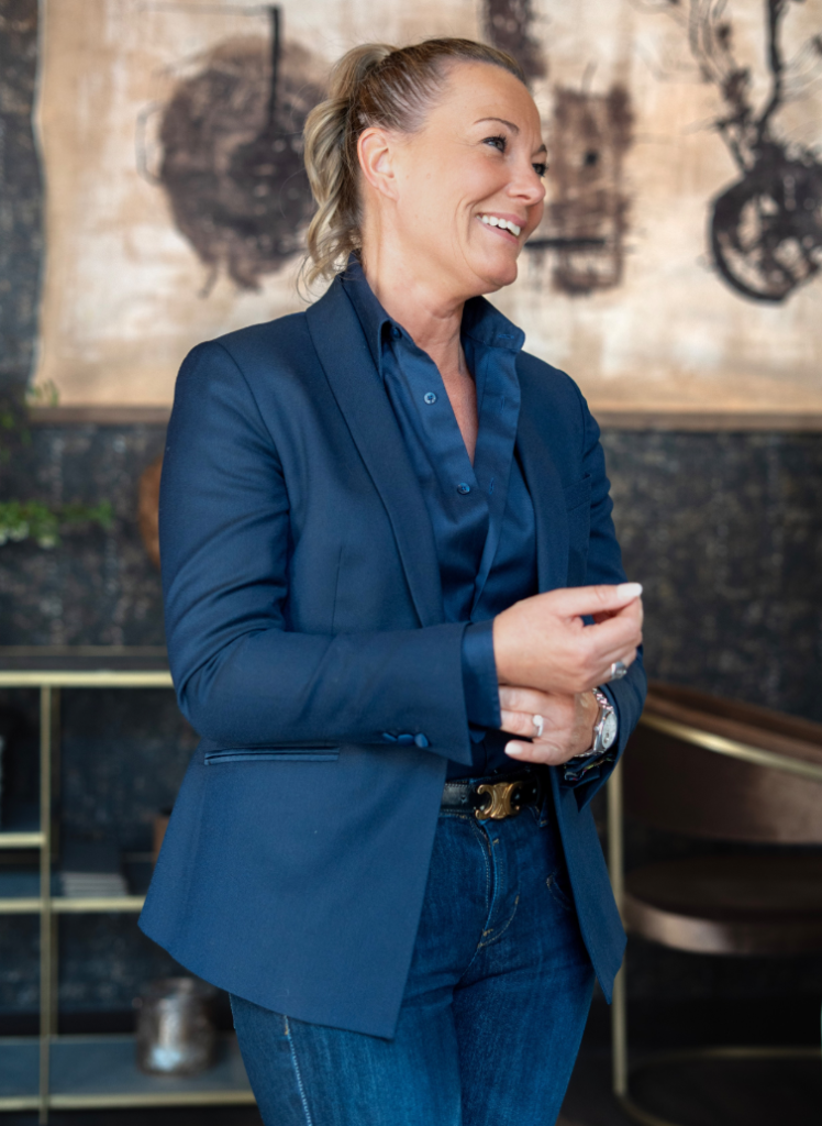 Femme portant une veste bleu marine sur mesure avec chemise satinée bleue et jean.