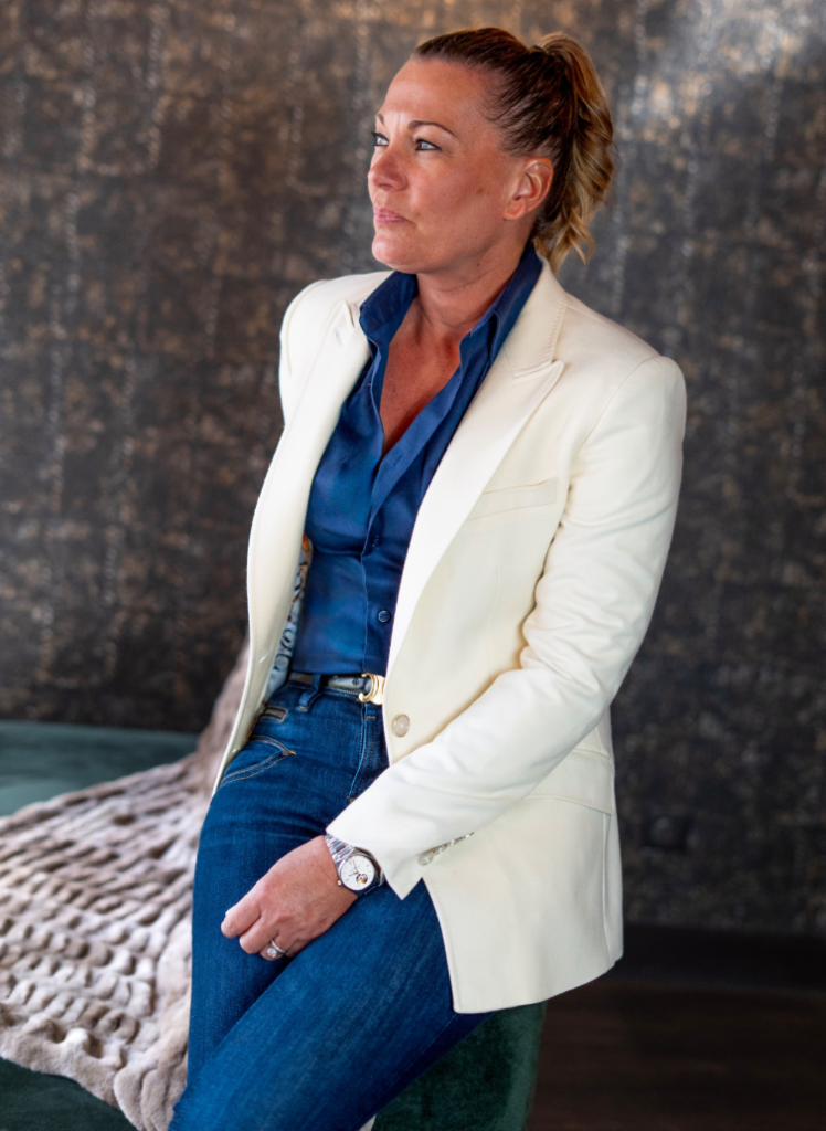 Femme portant une veste blanche sur mesure avec chemise bleue et jean.