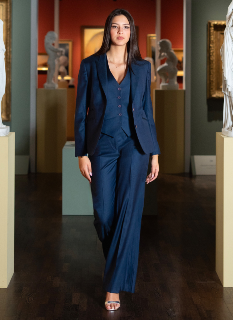 Femme portant un costume bleu marine sur mesure avec veste, gilet et pantalon assorti.
