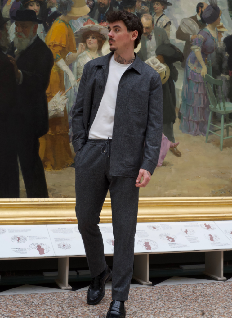 Homme portant un ensemble gris anthracite sur mesure avec veste légère, pantalon coordonné et t-shirt blanc.